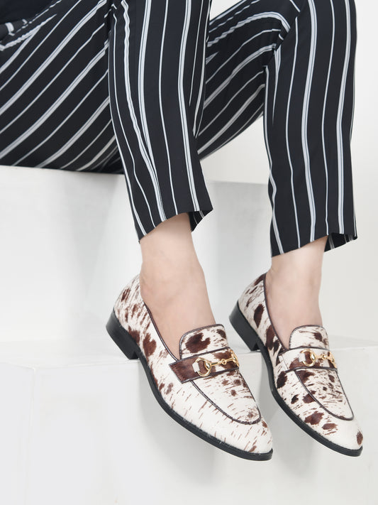 Person wearing patterned loafers and black and white striped pants on a light background
