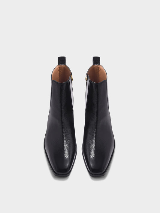 Pair of a black patent leather boots with side zipper on a mid heel