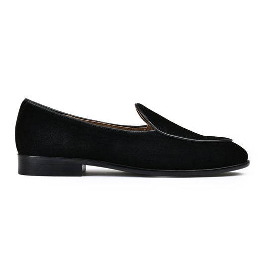 Black loafer shoe with a gold buckle on a white background