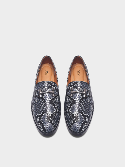 Pair of snake print horsebit loafers on a light gray background