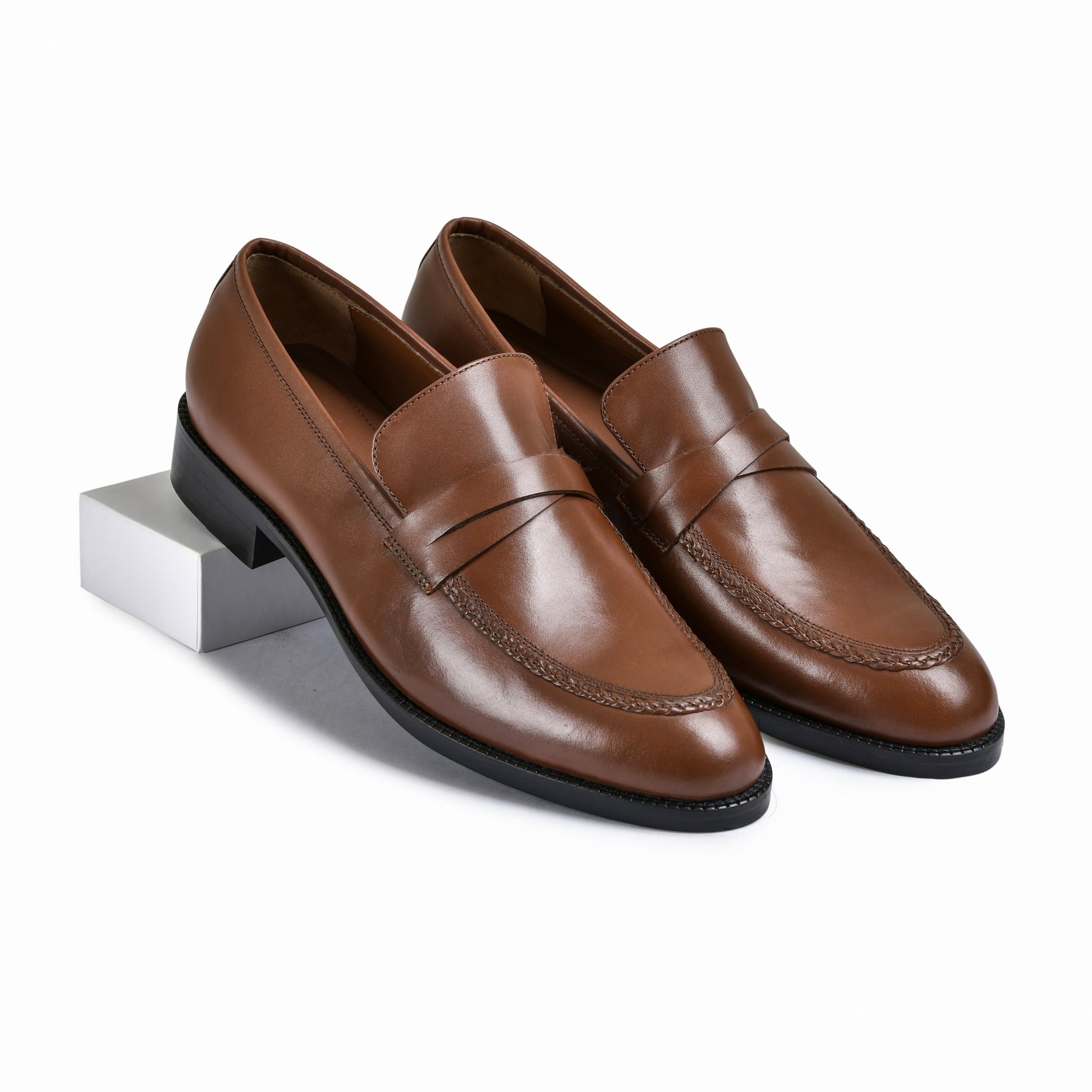 Pair of brown leather loafers on a white background