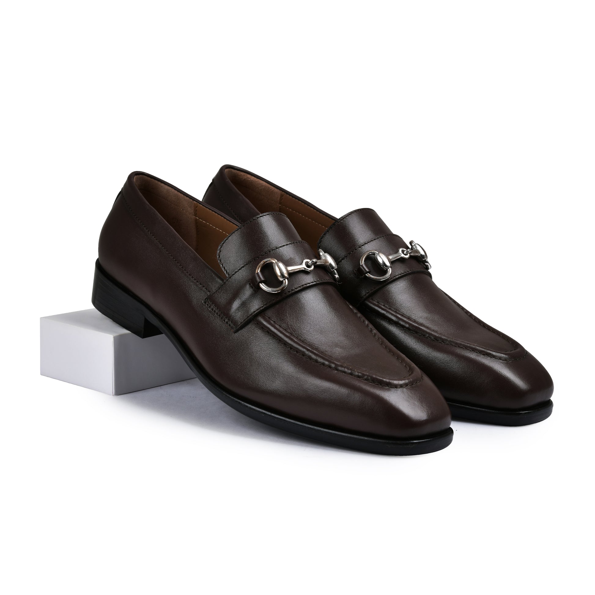 Pair of brown leather loafers with a metallic buckle on a white background