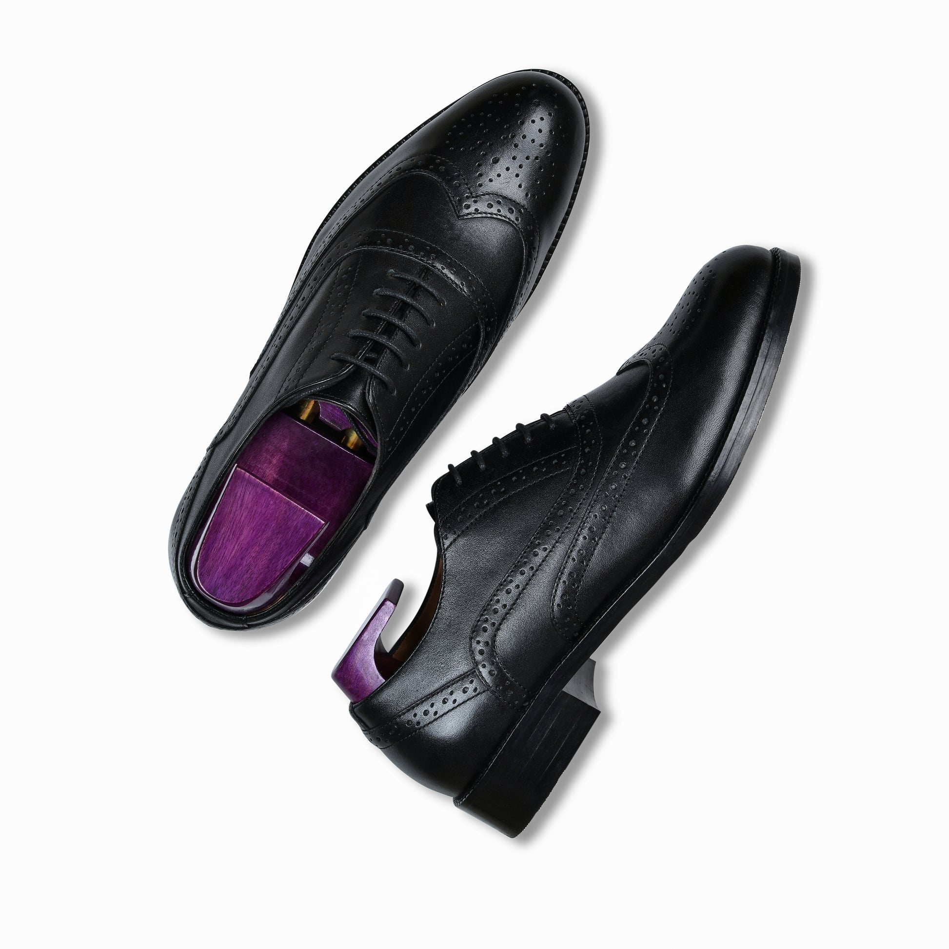 Black dress shoes with purple soles on a white background