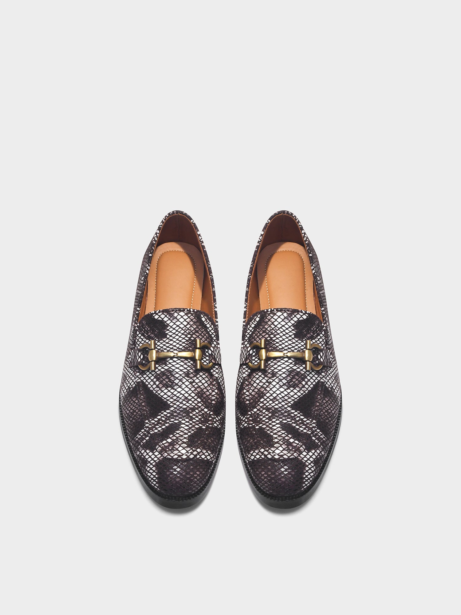 Pair of patterned loafers with gold accents on a light gray background