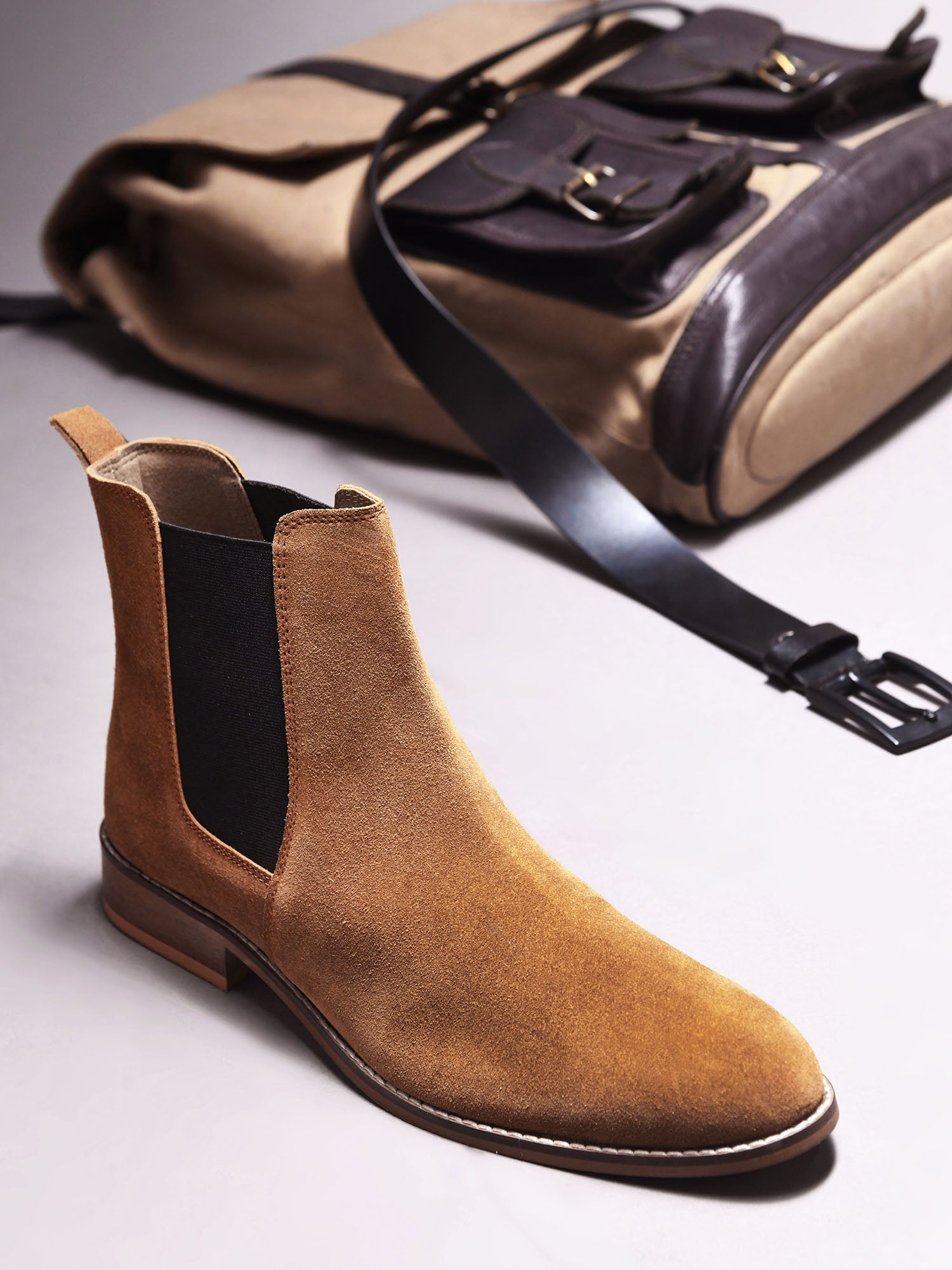 A men's luxury suede leather Chelsea boot with a mid heel and elastic side panels, in a tan color.