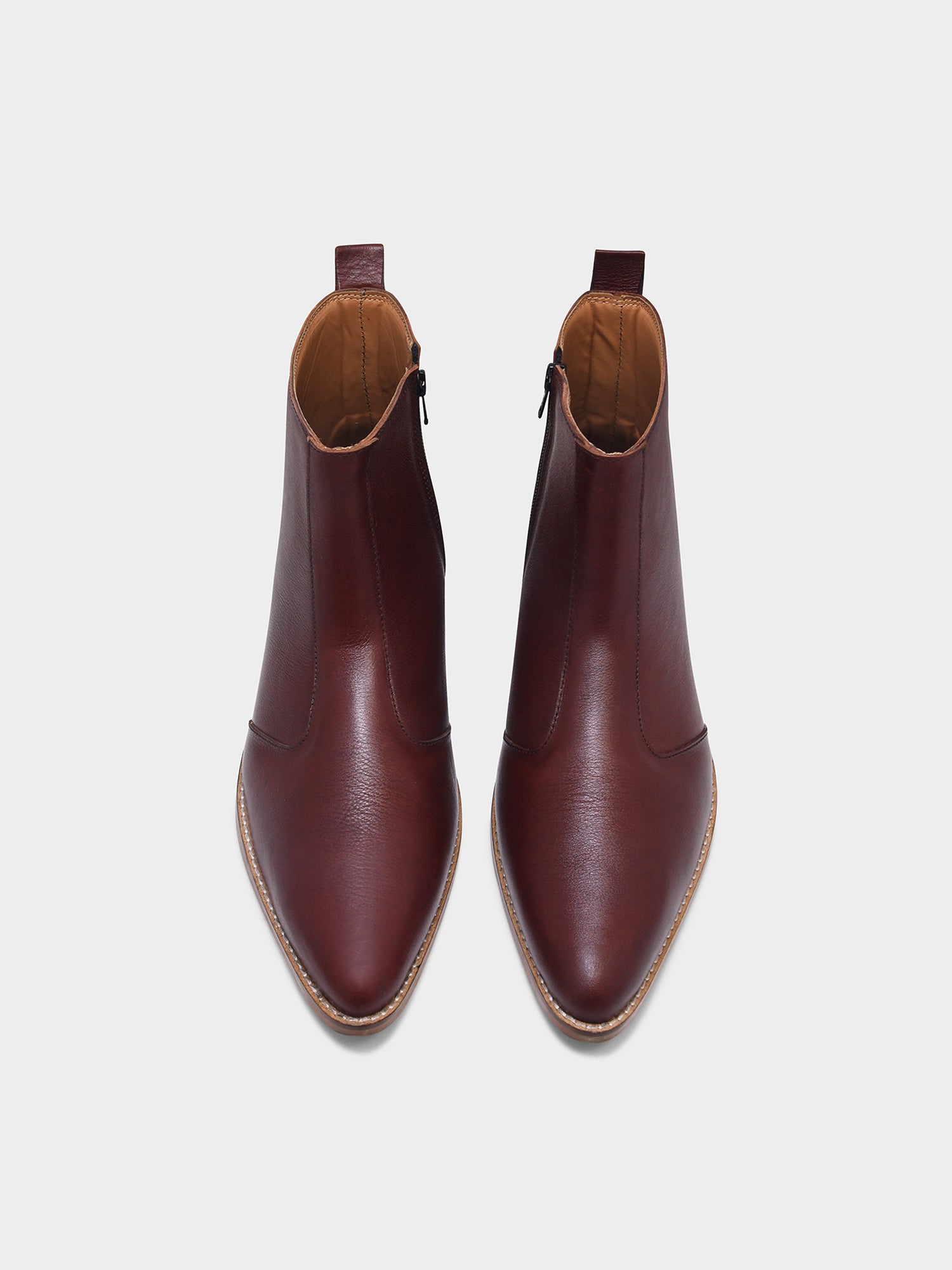 Pair of brown leather ankle boots on a light gray background