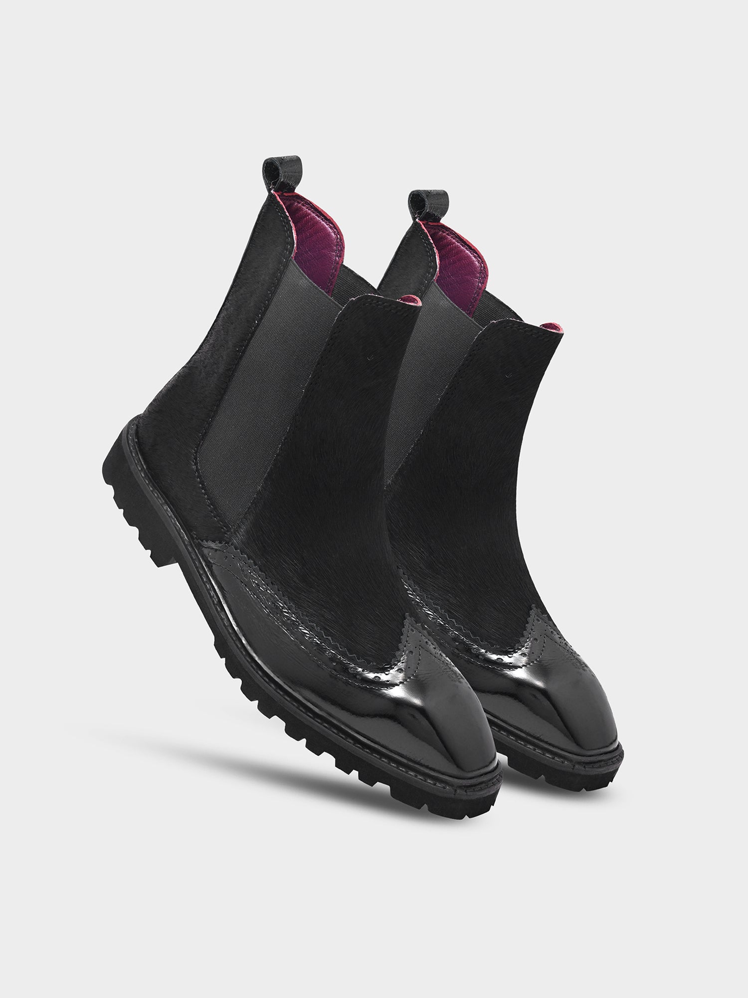 Black slip-on boots with purple lining on a light gray background
