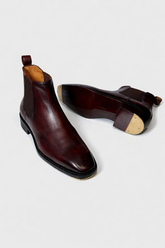 Pair of brown leather boots with black soles on a white background
