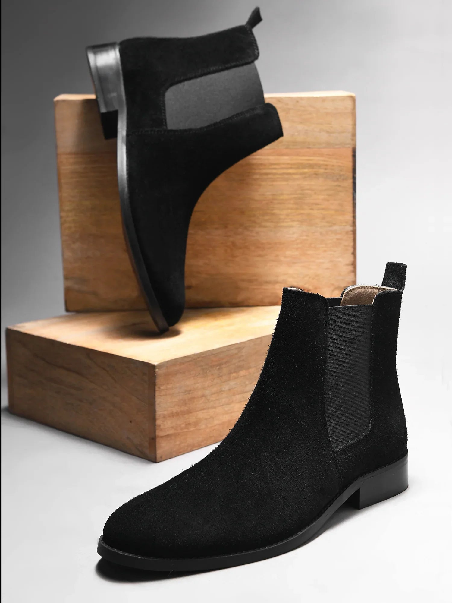 A men's luxury suede leather Chelsea boot with a mid heel and elastic side panels, in a black color.