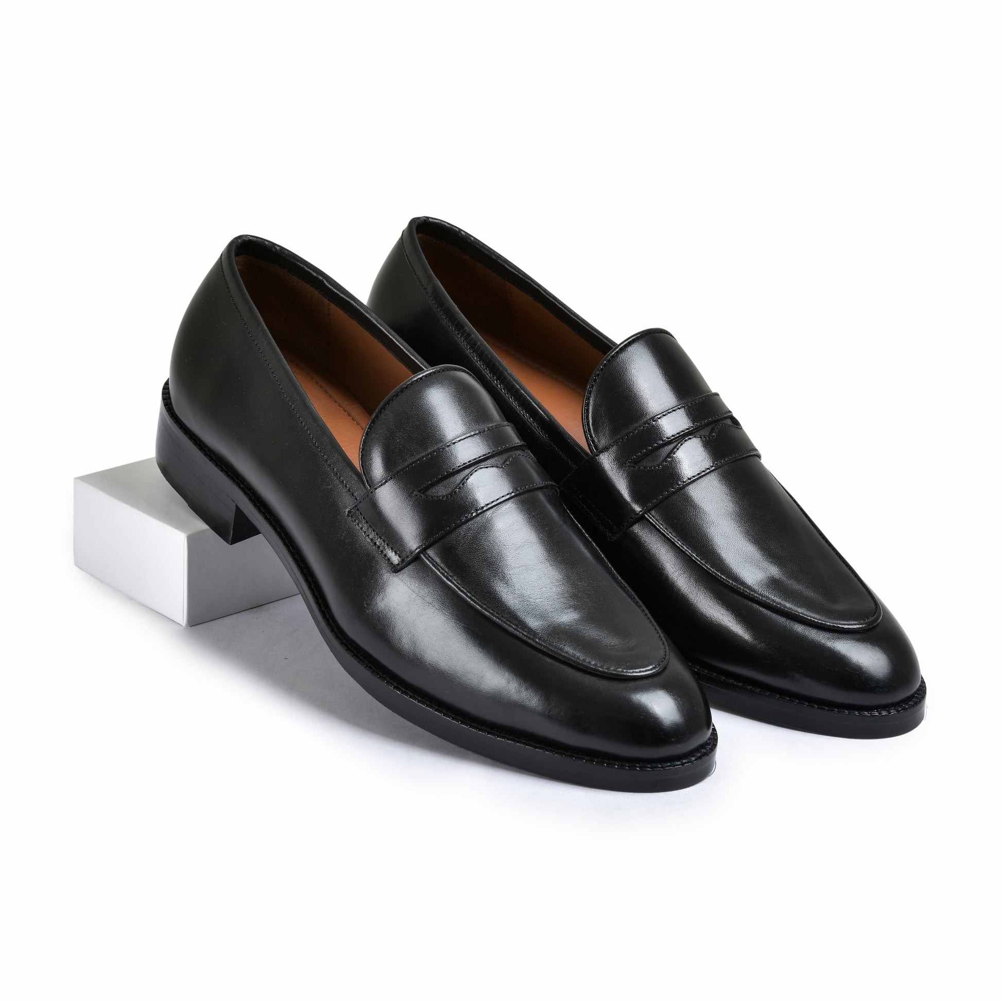 Pair of black leather loafers on a white background