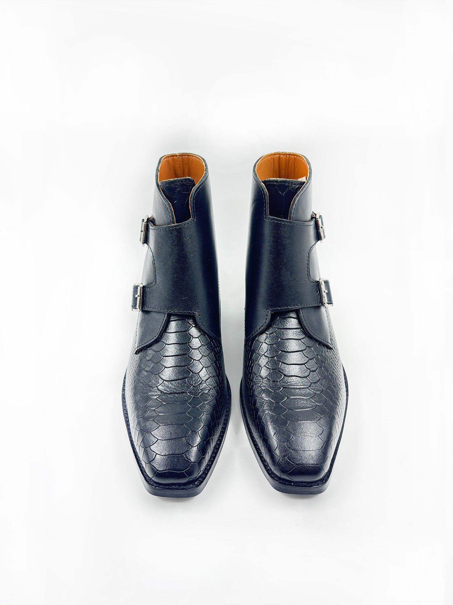 Pair of black leather boots with snake skin pattern on a white background