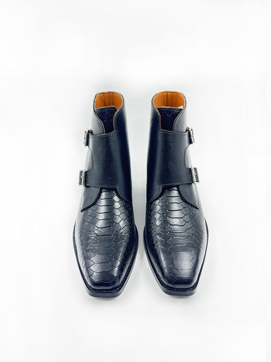 Pair of black leather boots with snake skin pattern on a white background