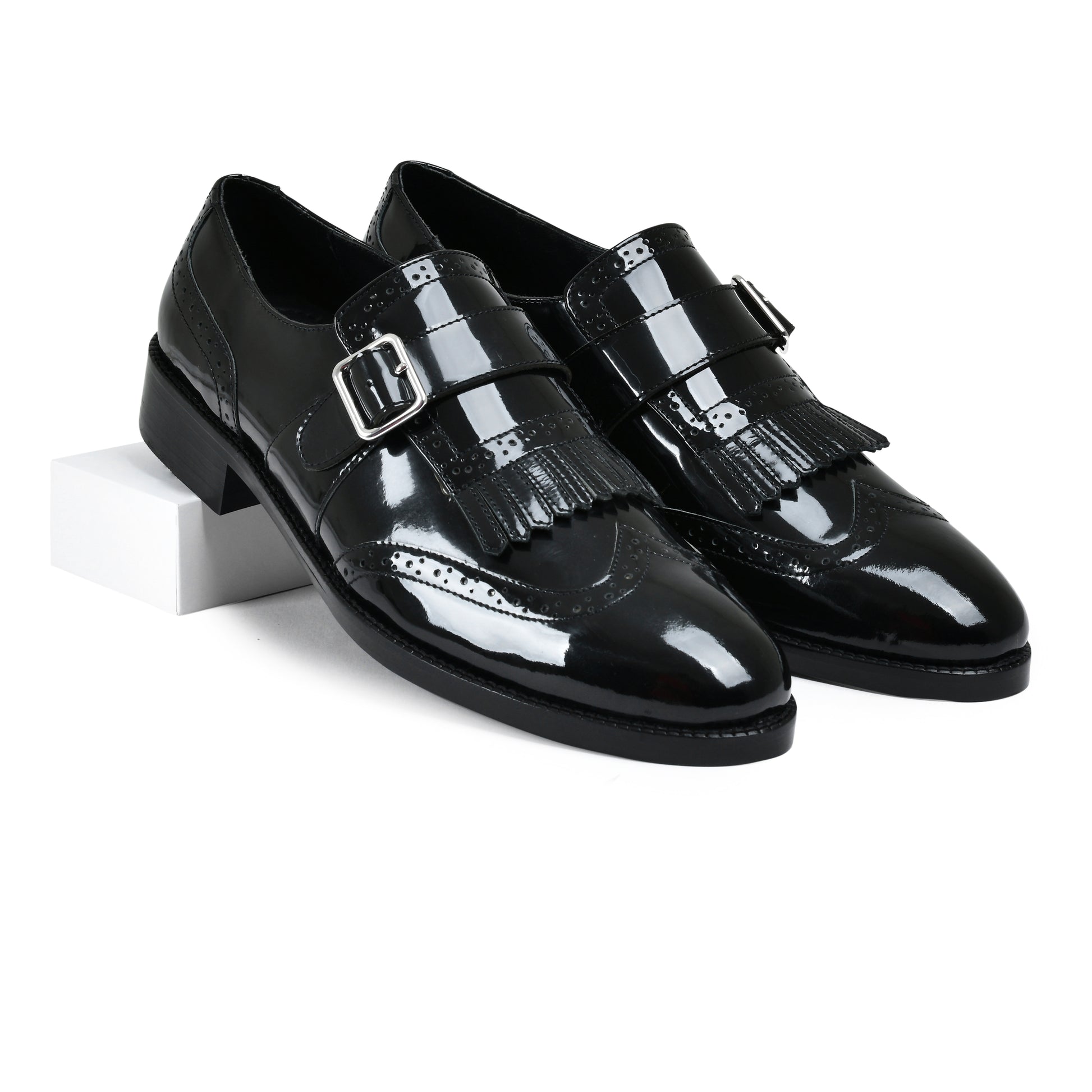 Pair of black patent leather shoes with buckles on a white background