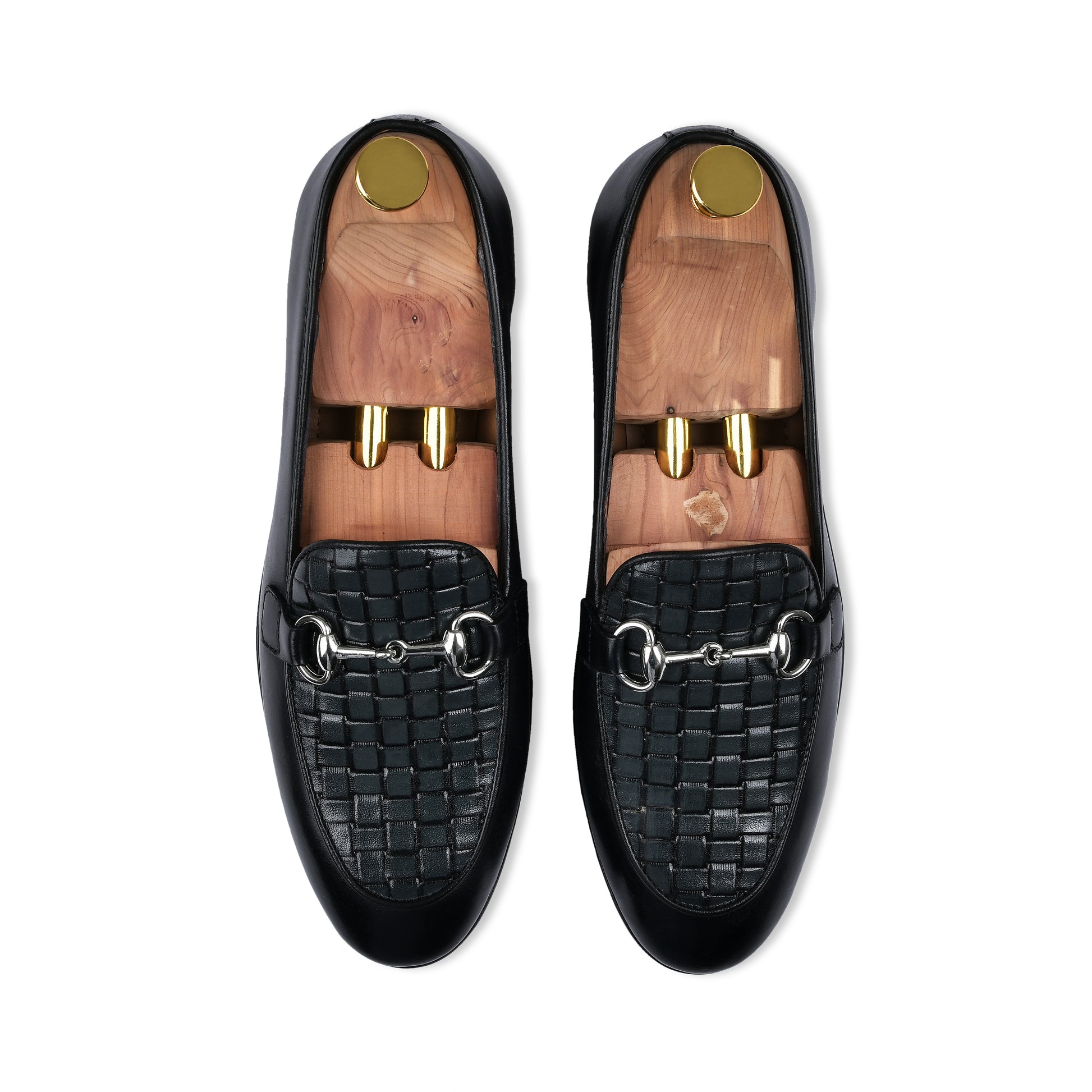 Black loafers with woven pattern and gold accents on a white background