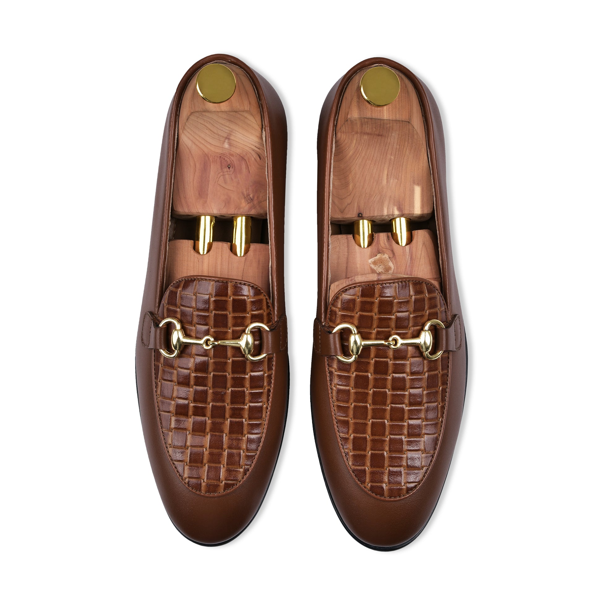 Pair of brown loafers with gold hardware on a white background