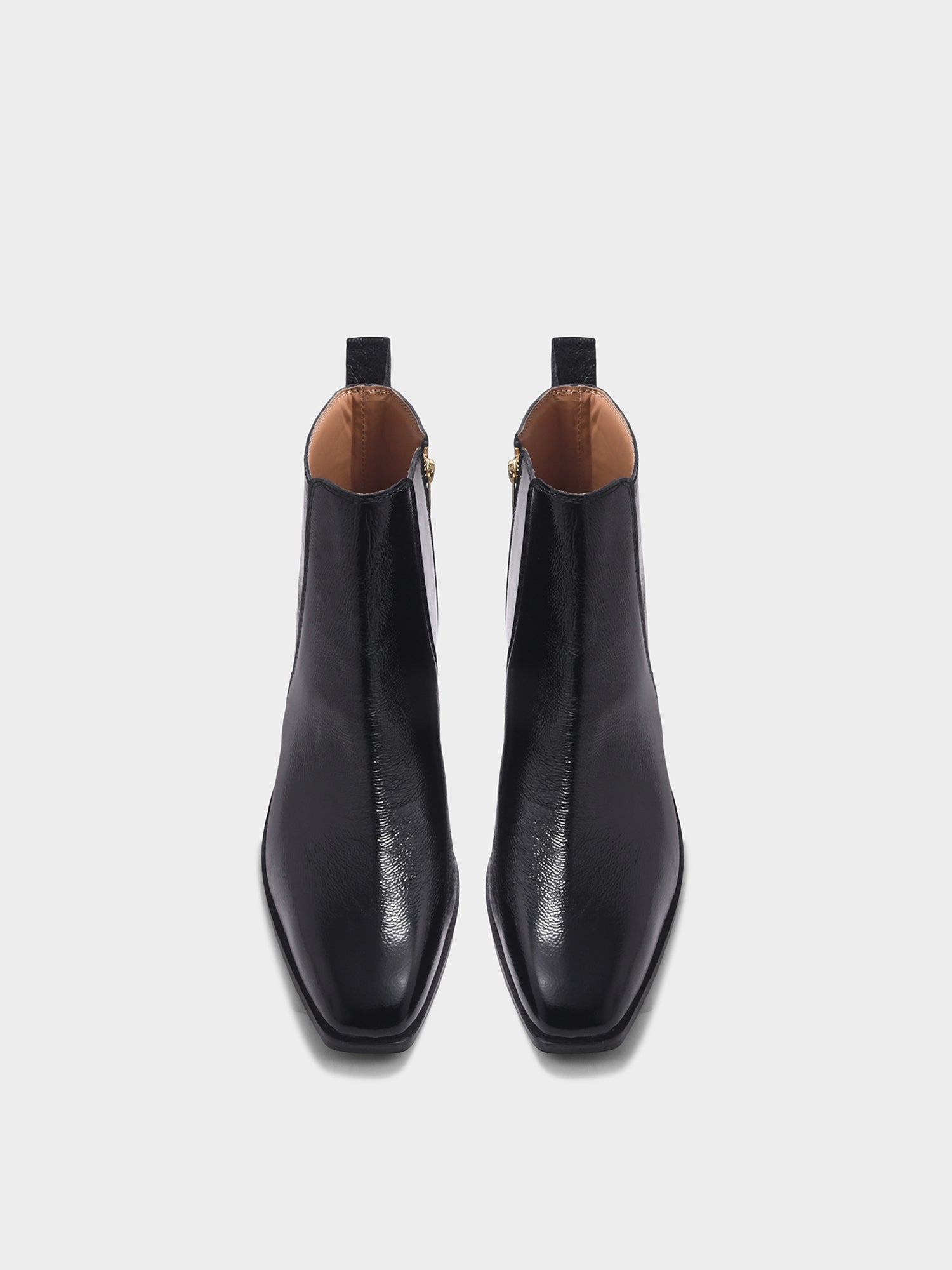 Pair of a black patent leather boots with side zipper on a mid heel