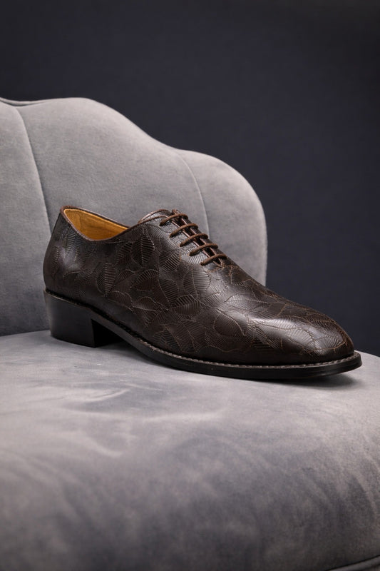 Brown leather shoe on a gray surface with a dark background