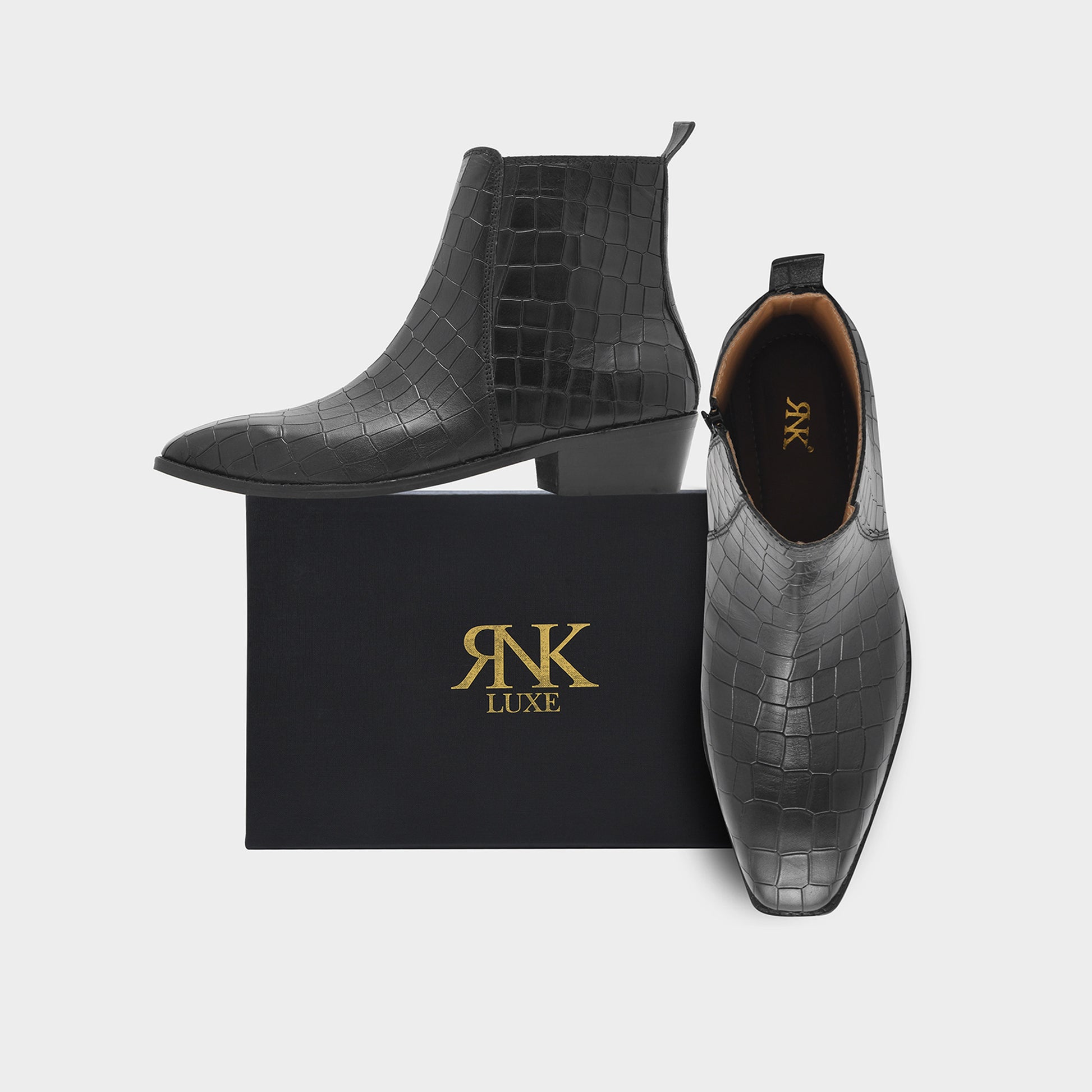 Black crocodile-patterned ankle boots with 'R&K Luxe' branding on a white background