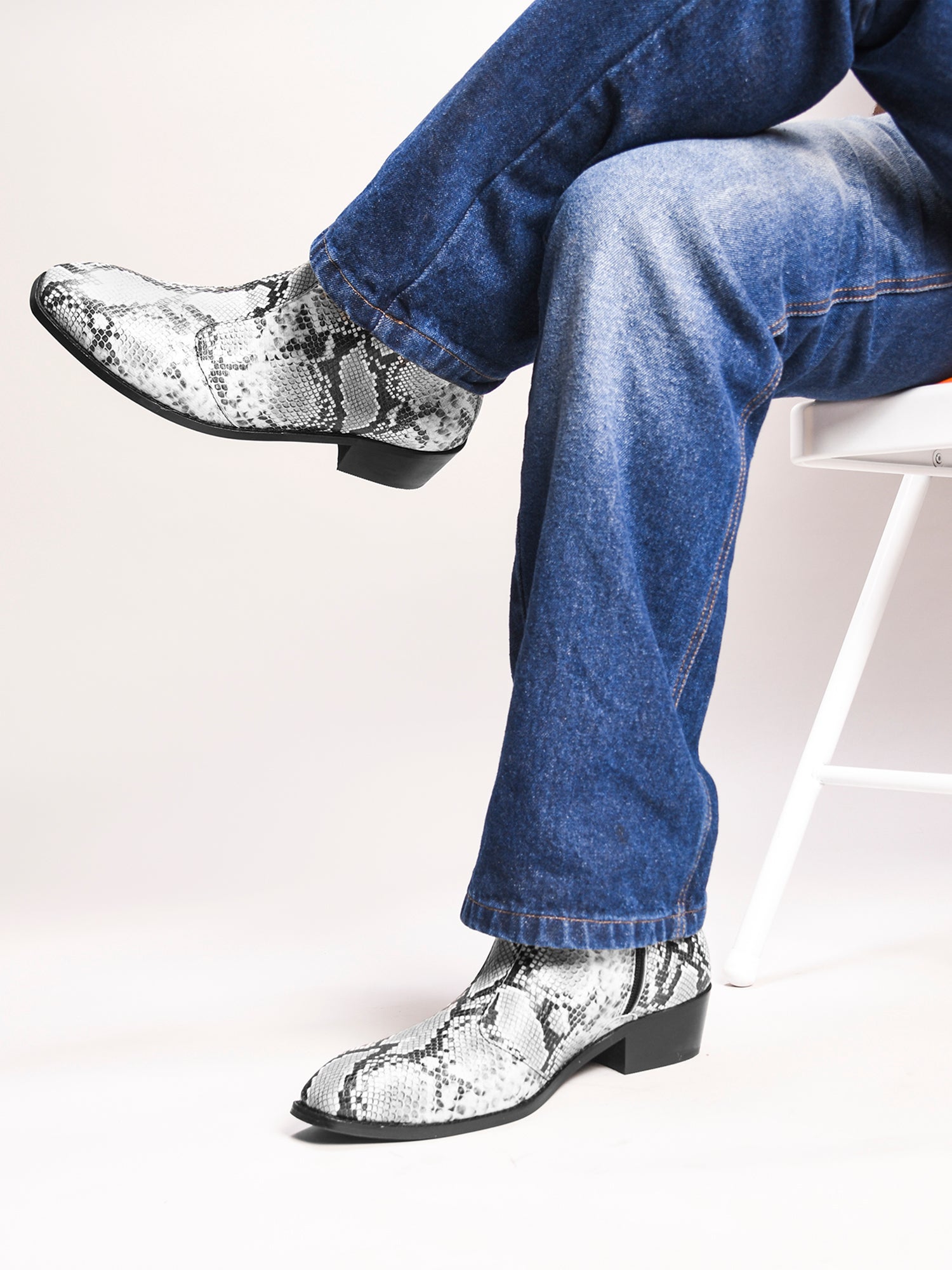 A pair of black and white snake printed leather boot with square toe and a black colour Cuban heel