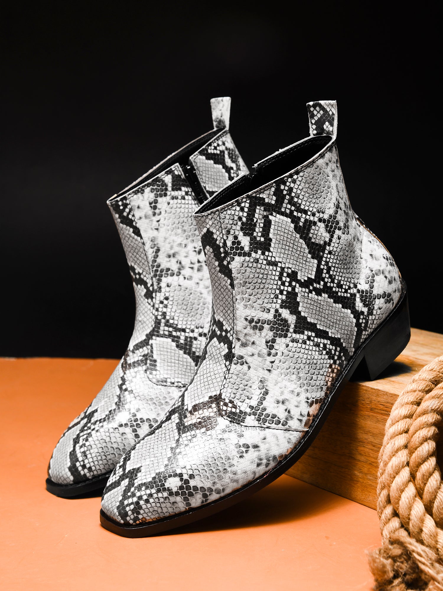 A pair of black and white snake printed leather boot with square toe and a black colour Cuban heel
