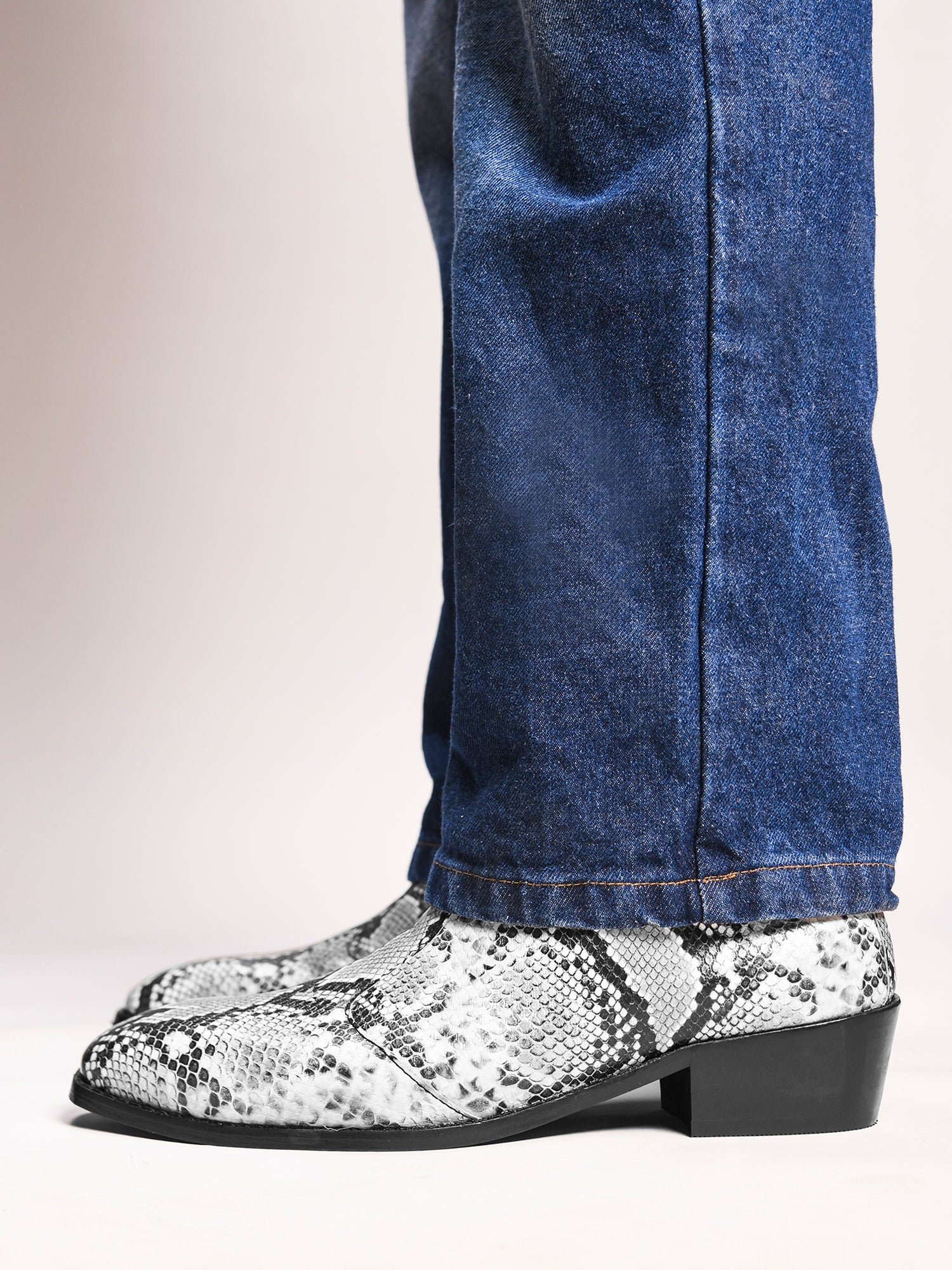 A pair of black and white snake printed leather boot with square toe and a black colour Cuban heel