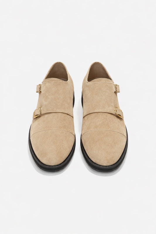 Pair of beige suede shoes with black soles on a white background