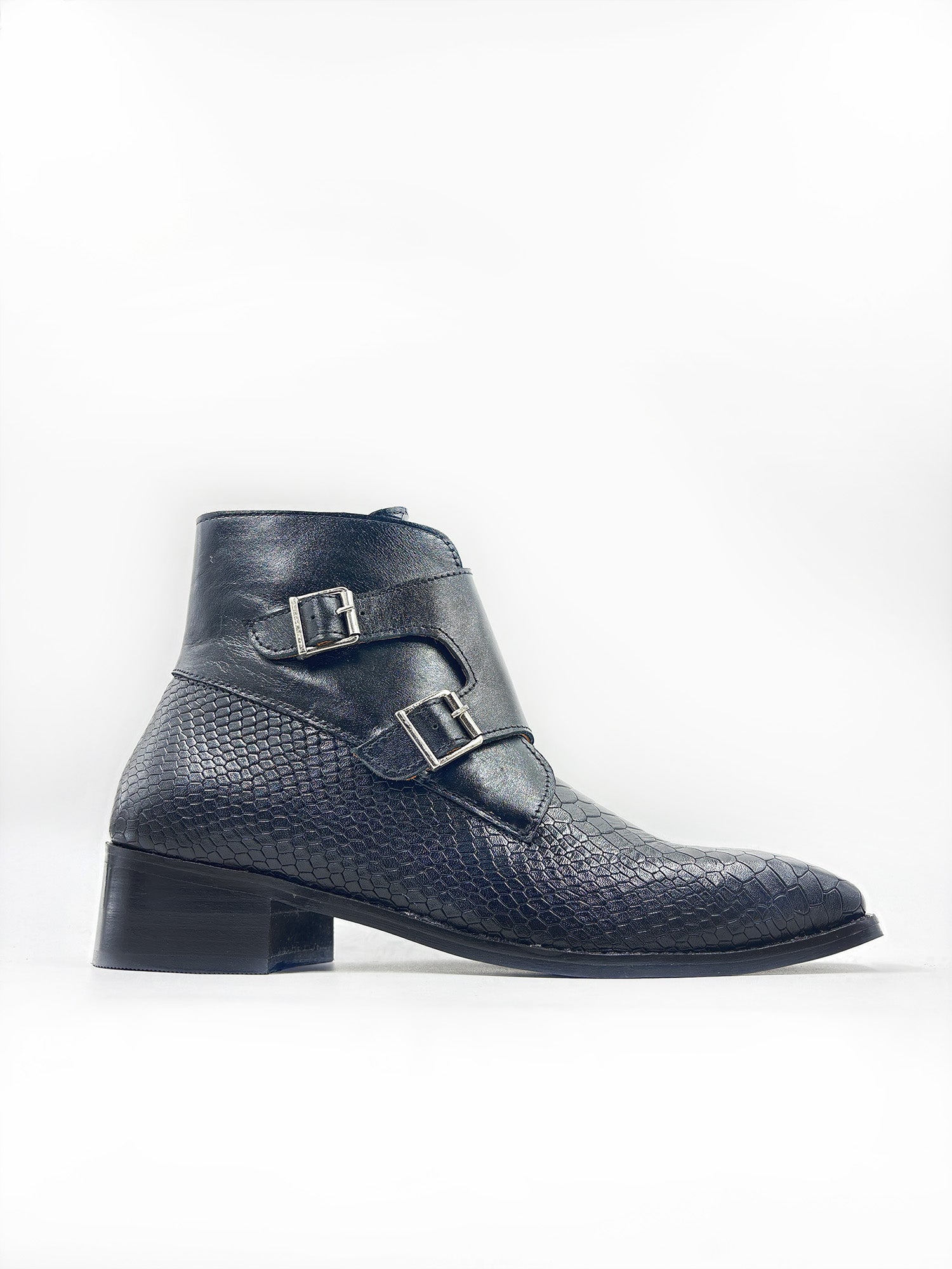 Black textured ankle boot with silver buckles on a white background