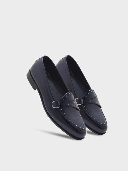 Pair of black loafers with a buckle on a light gray background