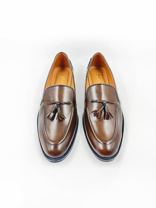 Pair of brown leather loafers with tassels on a white background
